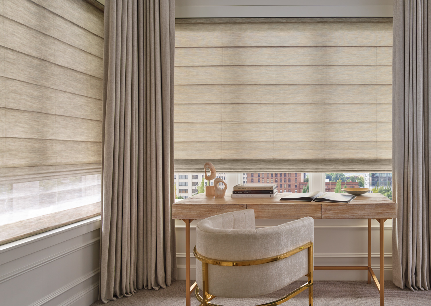 A bedroom with a desk and chair in front of window with Hunter Douglas Alustra® Woven Textures® Roman Shades.