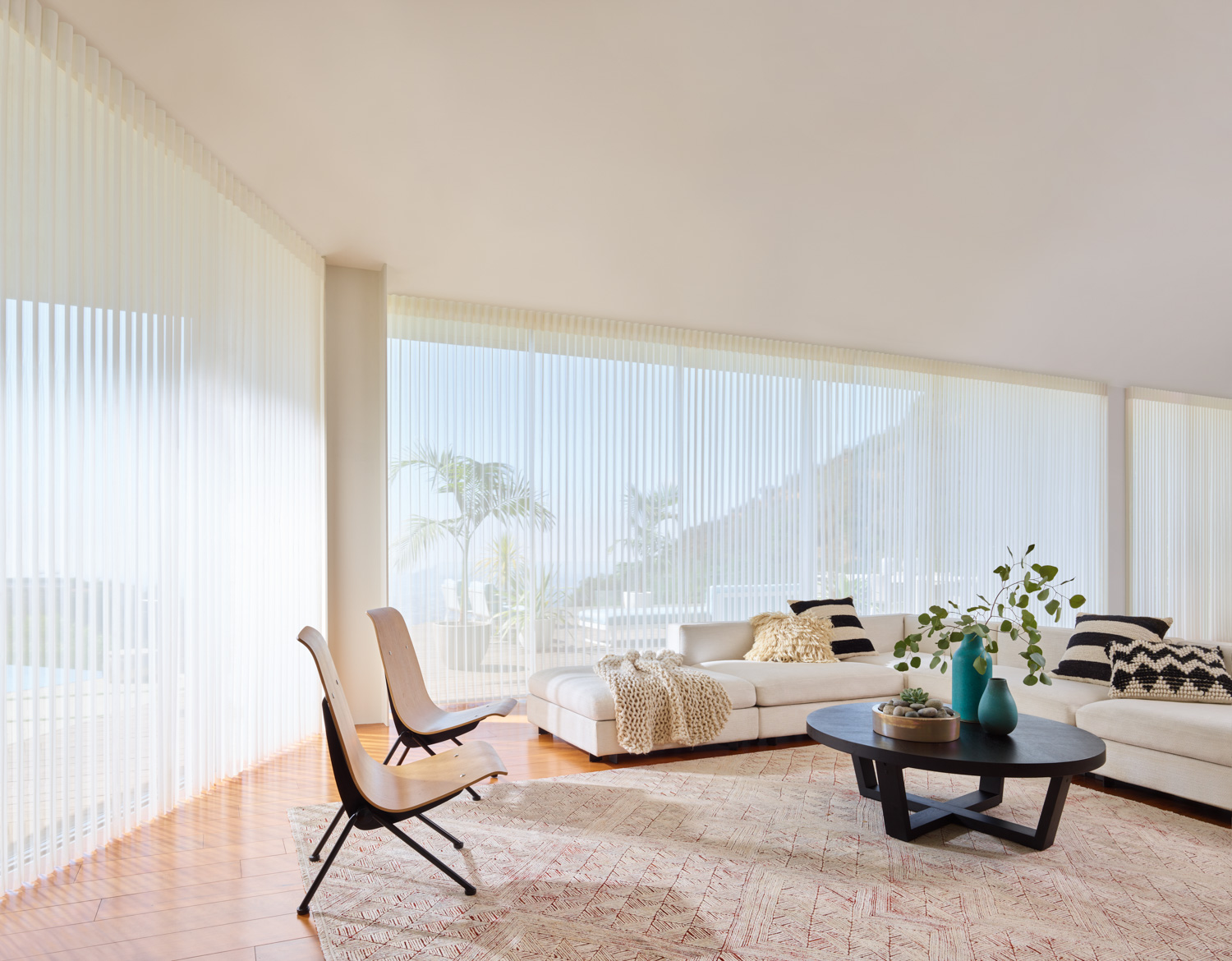 A living room with white furniture and large windows, featuring Hunter Douglas Luminette® Sheer Panels.