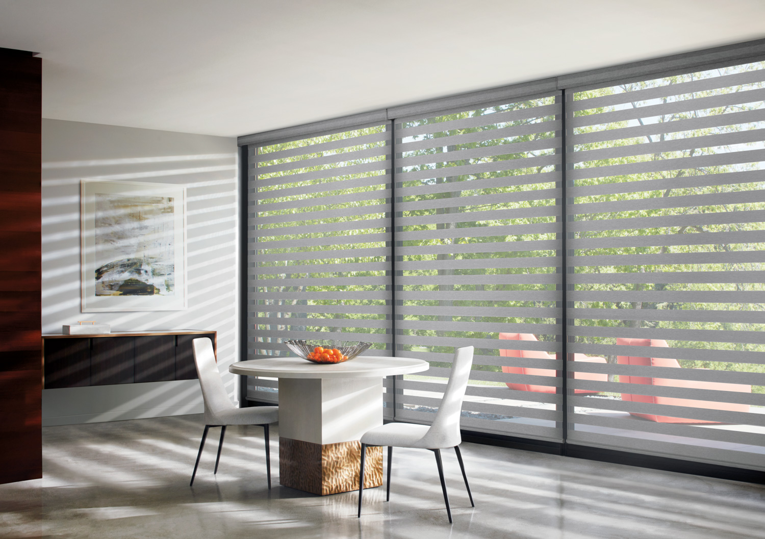 Dining room with table and chairs in front of large window, featuring Hunter Douglas Designer Banded Shades.