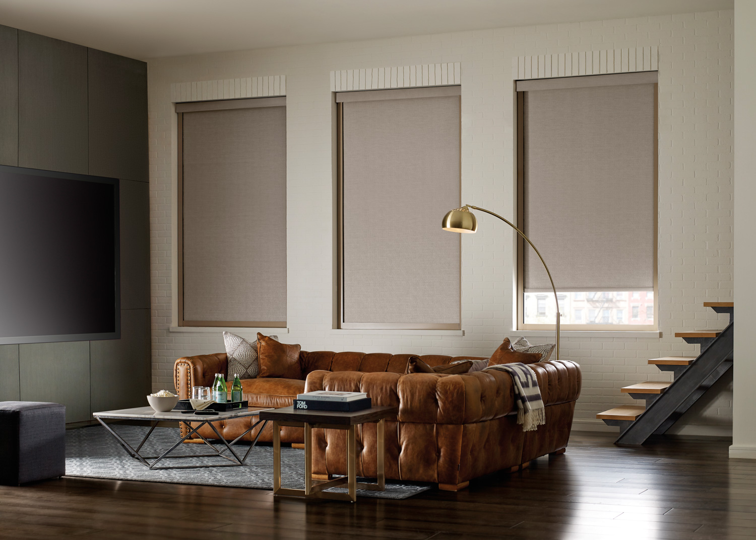 A cozy living room with a couch, TV, and window showcasing Hunter Douglas Designer Roller Shades.