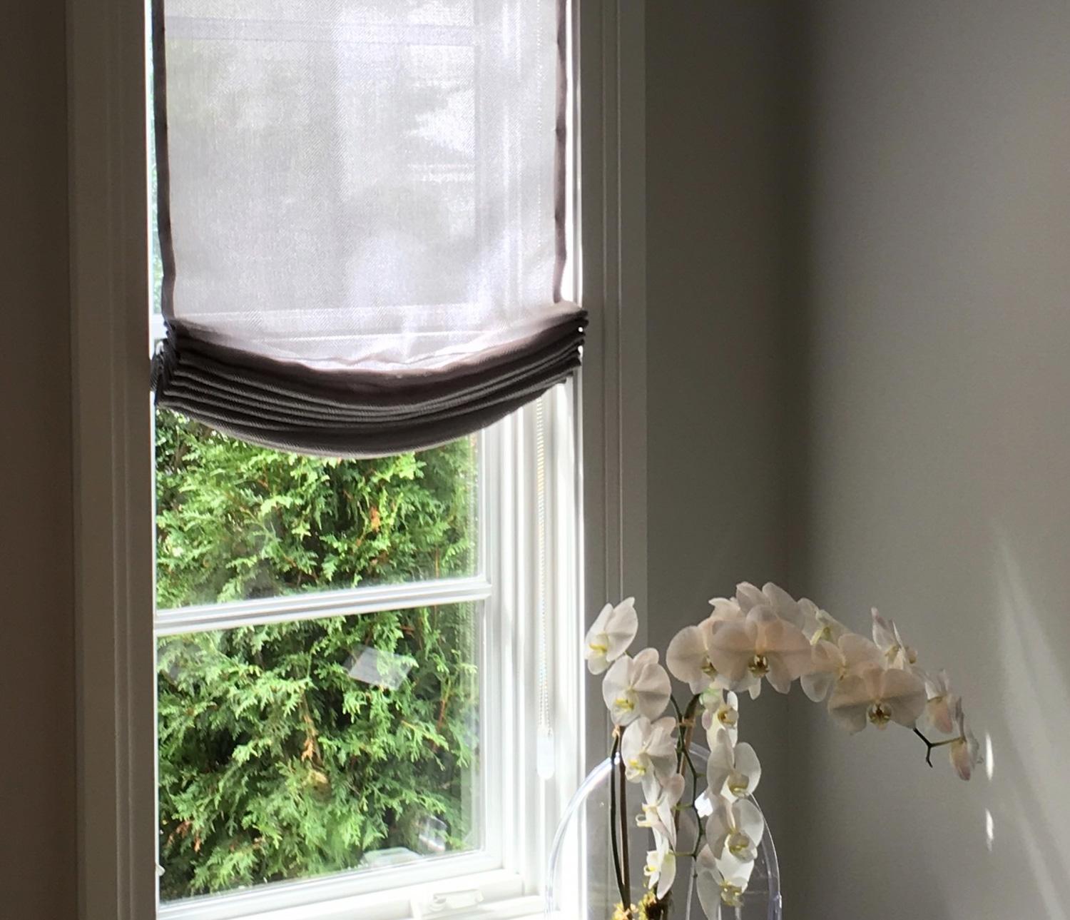 White vase on windowsill with Fabric Roman Shades in background.