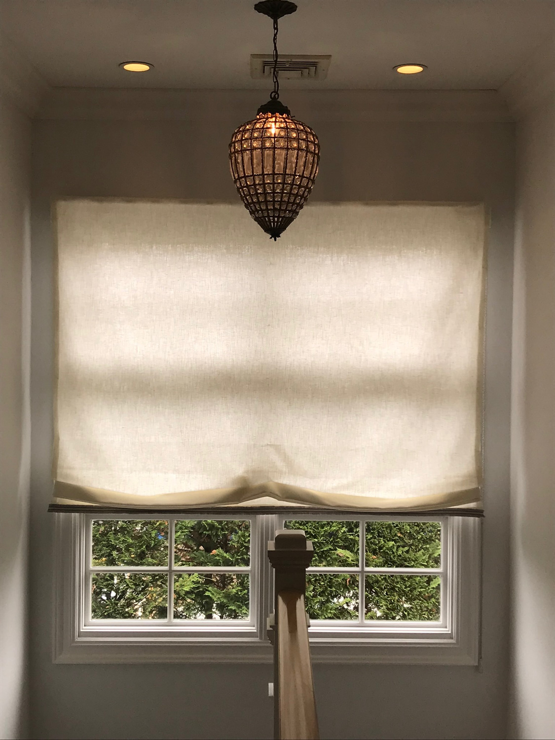 Window with fabric roman shade and lamp.