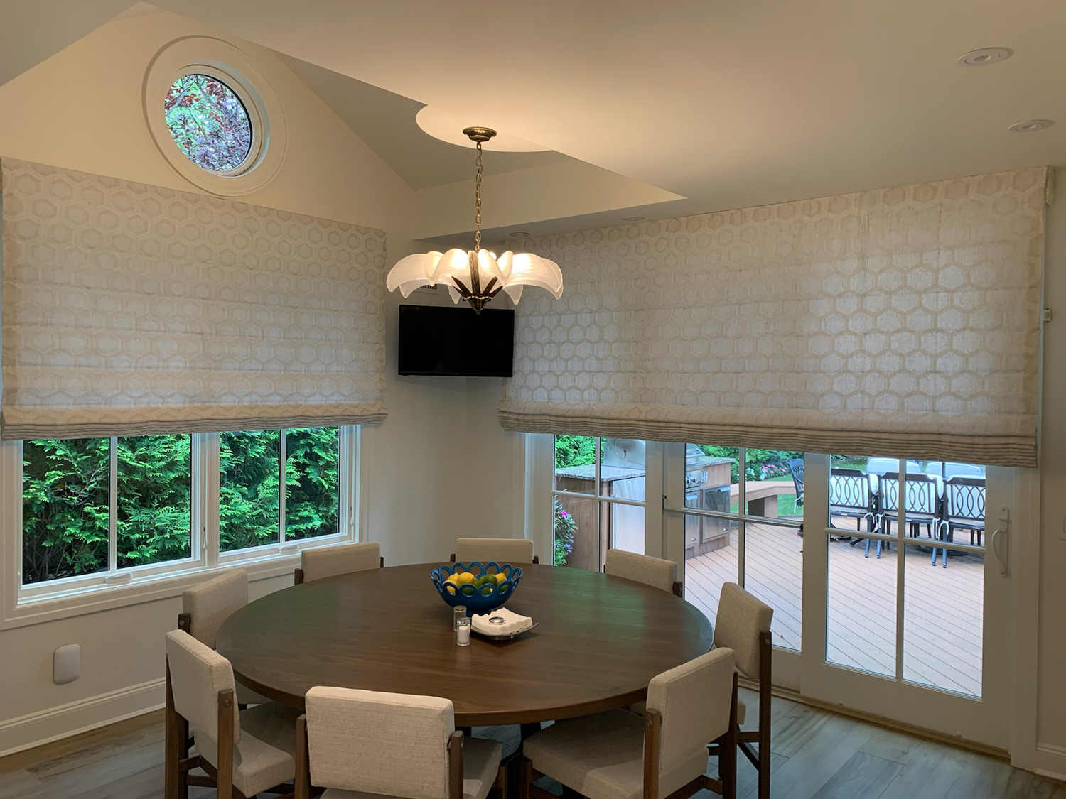 A dining room with a table and chairs, adorned with Fabric Roman Shades, creating a cozy and stylish ambiance.