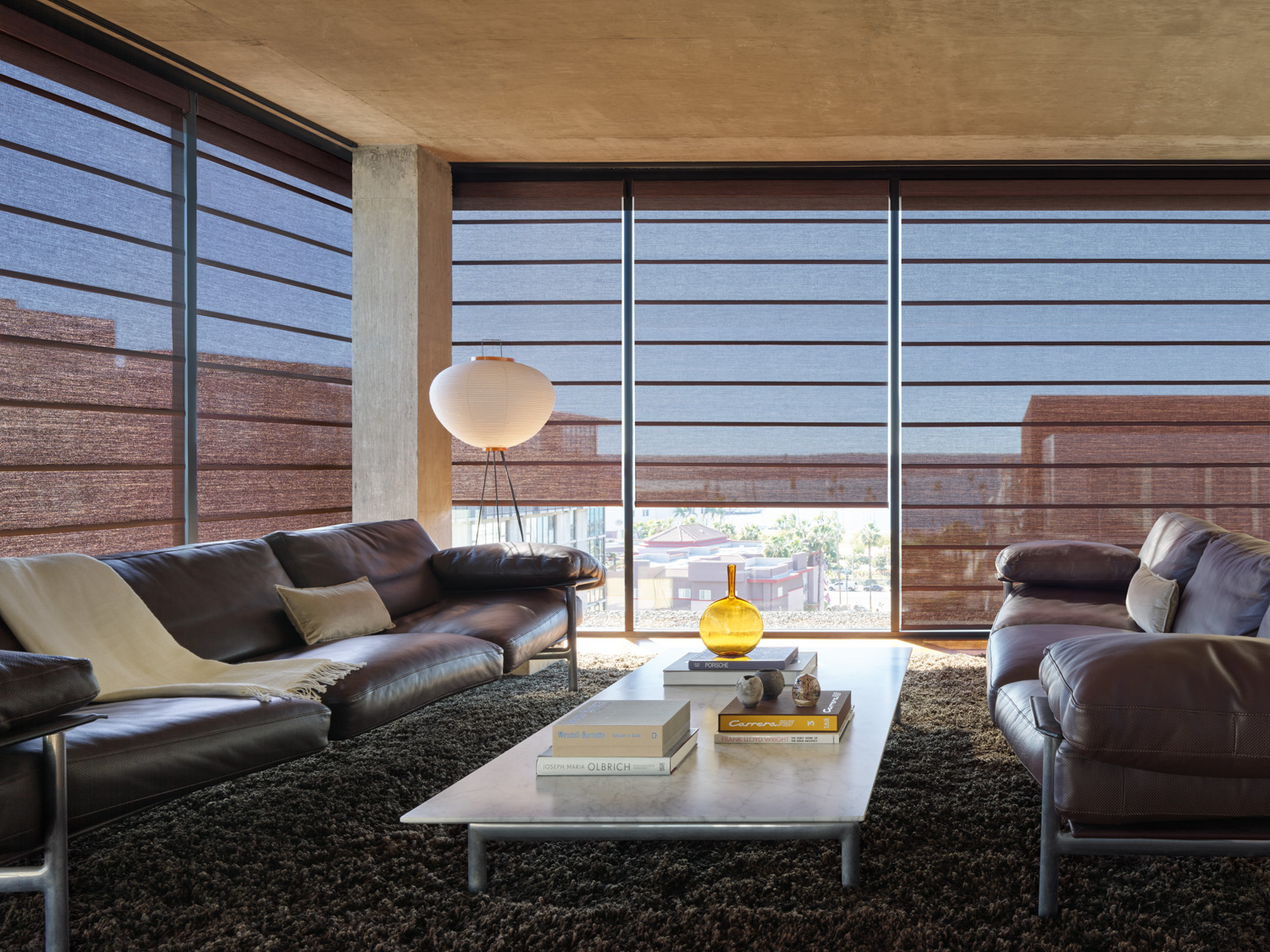 Leather sofas and large window in living room with Hunter Douglas Alustra® Architectural Roller Shades.