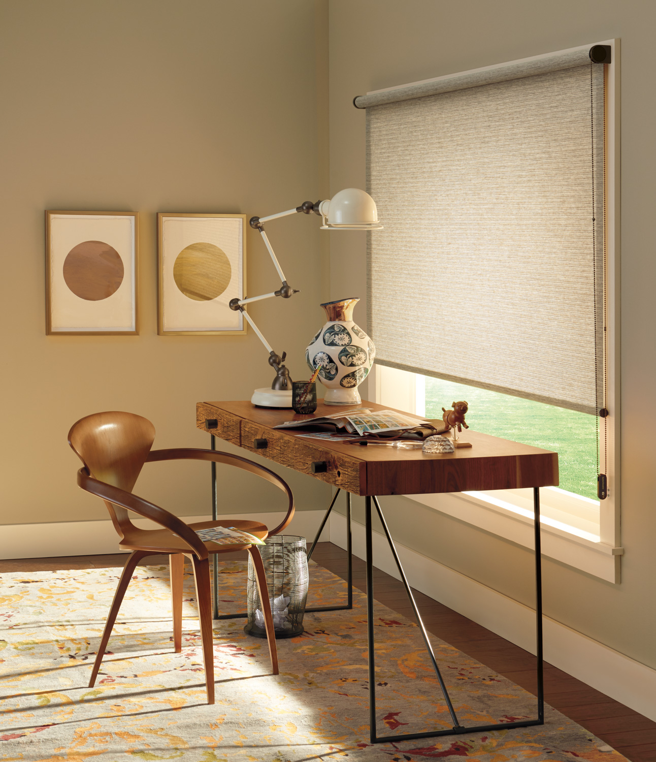 A desk with a chair and a lamp in front of a window, with Hunter Douglas Alustra® Woven Textures® Roller Shades.