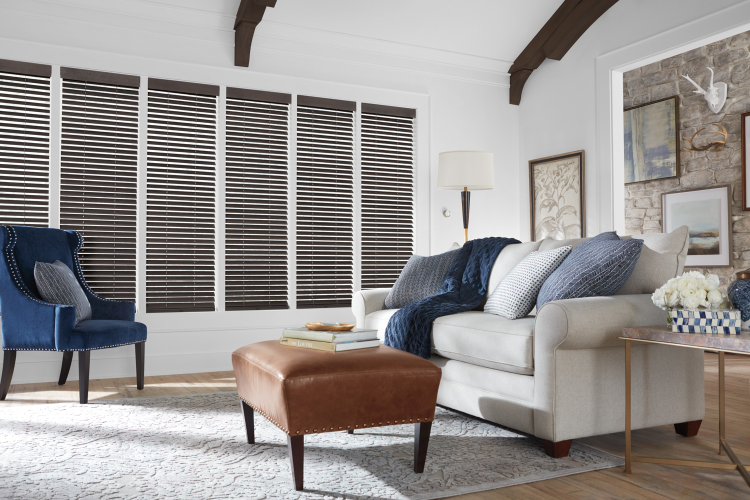 Lounge area featuring couch, chair, and Hunter Douglas Parkland® Wood Blinds.