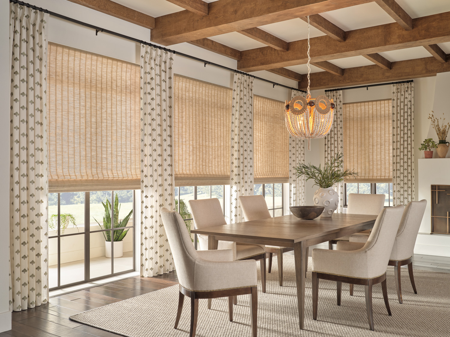 A well-appointed dining room showcasing a table and chairs, beautifully accentuated by the addition of natural woven wood Roman shades.