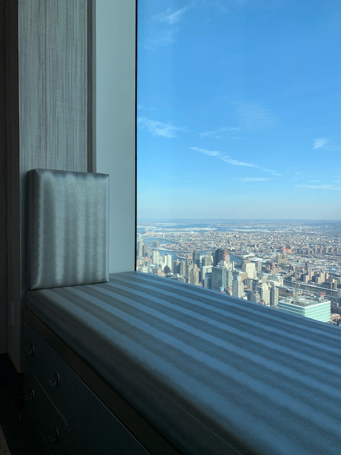 A custom upholstered bench cushion on a window seat overlooking a city skyline.