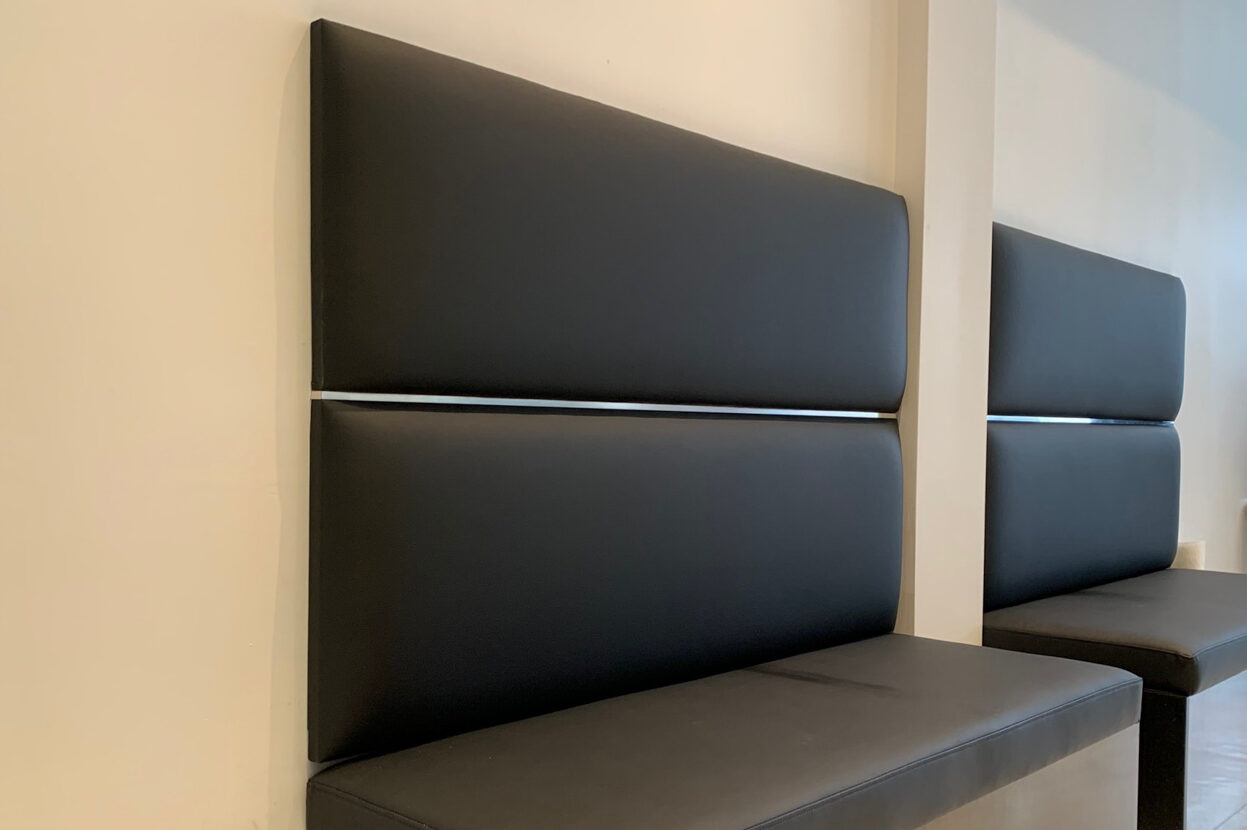 Black leather benches with Custom Upholstered Bench Cushion against a white wall in a room.