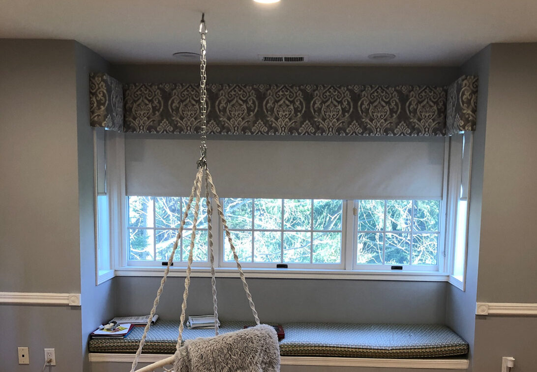 A custom upholstered cornice frames a window seat with a charming swing hanging next to it.