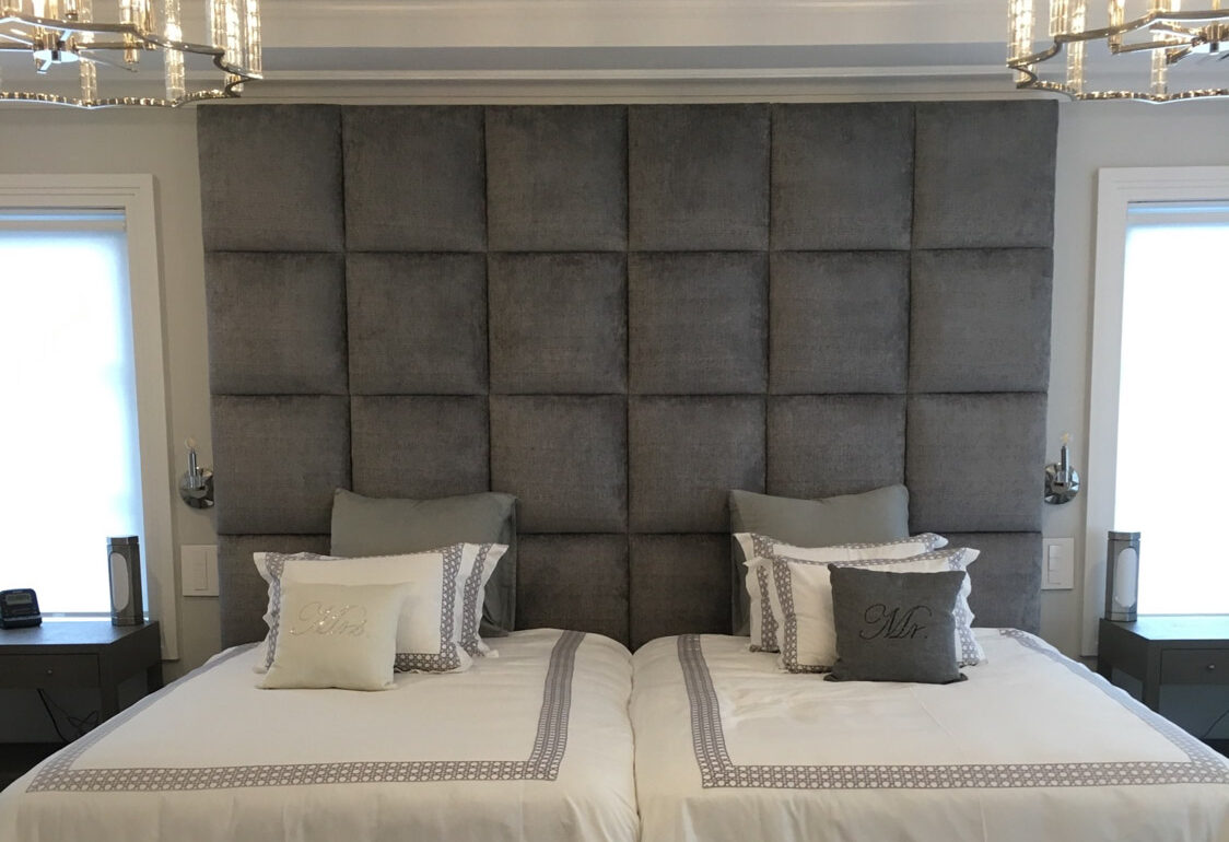 Luxurious custom upholstered headboard bed with two pillows and a chandelier.