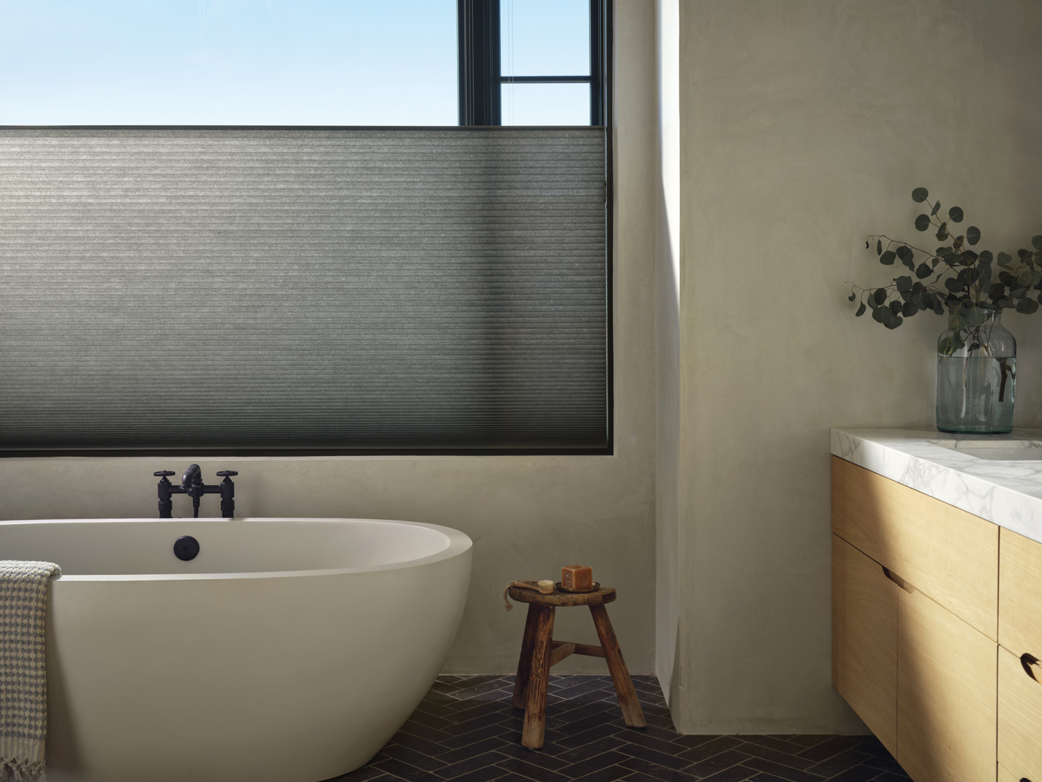 A bathroom with a window and a bathtub. The Hunter Douglas Duette® Honeycomb Shades add elegance and privacy.