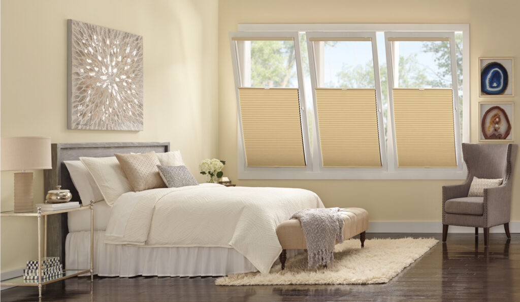 A bedroom with a bed, chair, and Hunter Douglas Duette® Honeycomb Shades, providing privacy and light control