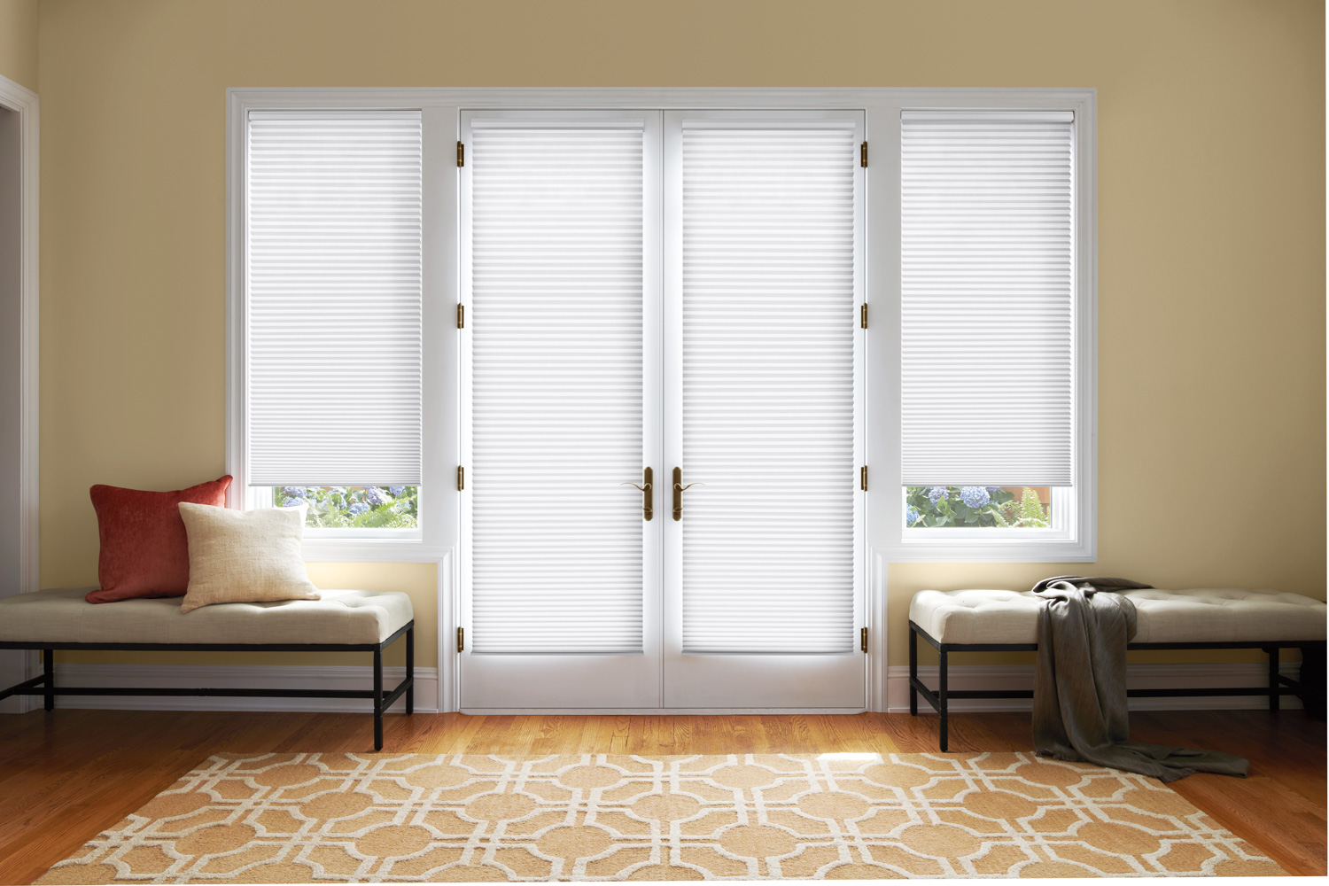White blinds and a bench in a room with Hunter Douglas Duette® Honeycomb Shades on doors.