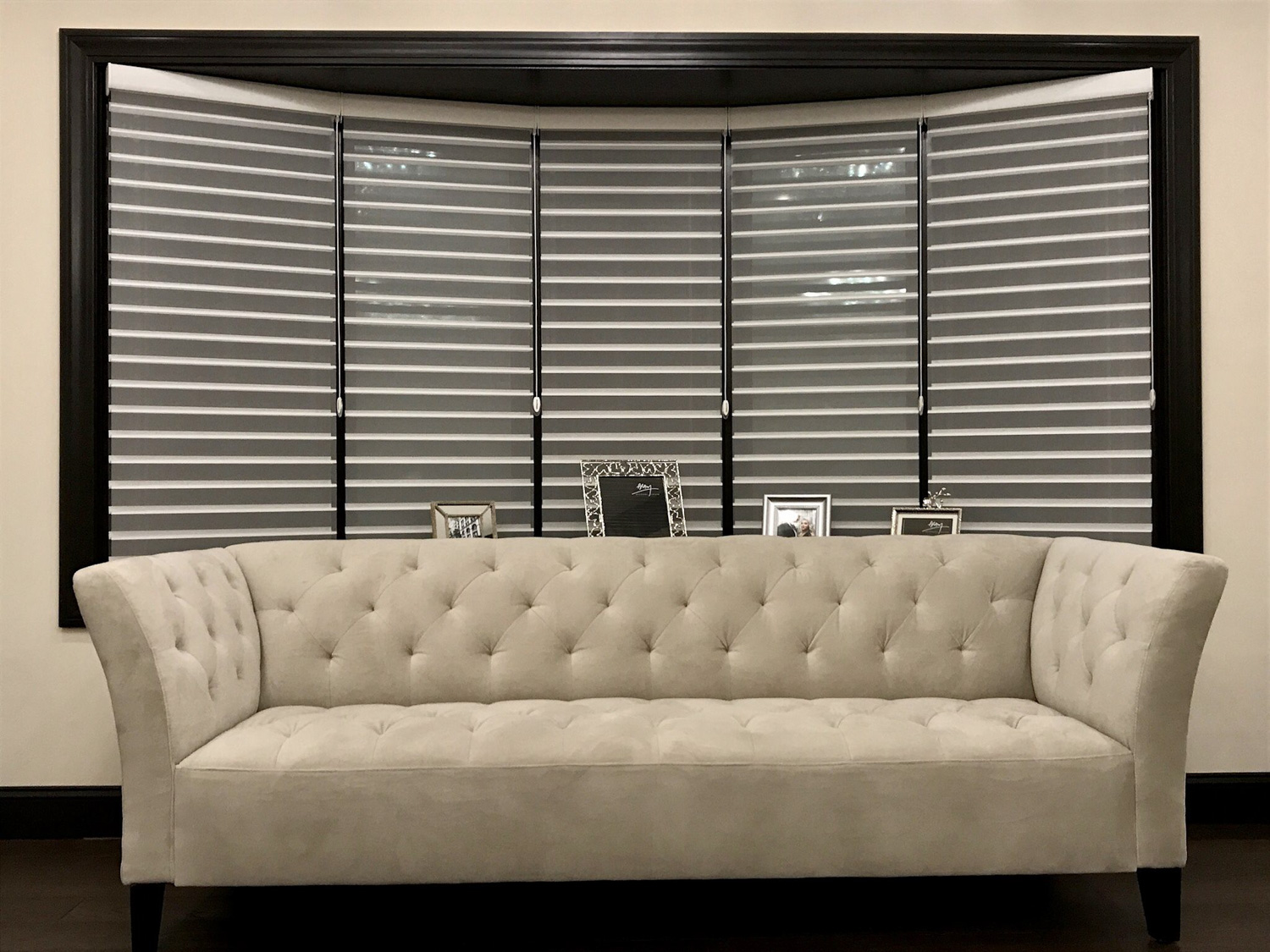 A stylish couch placed in front of a window with shades, featuring Hunter Douglas Silhouette® Window Shades in a bow window.