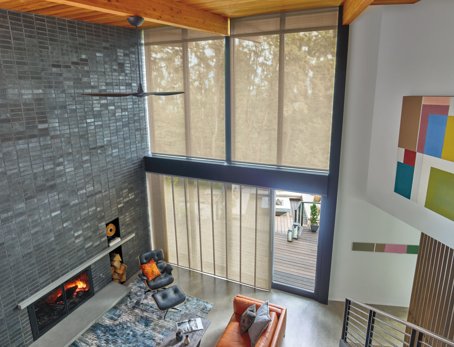 A cozy living room with a fireplace and a large window, complemented by Hunter Douglas Skyline® Panel-Track Blinds on the sliding door.