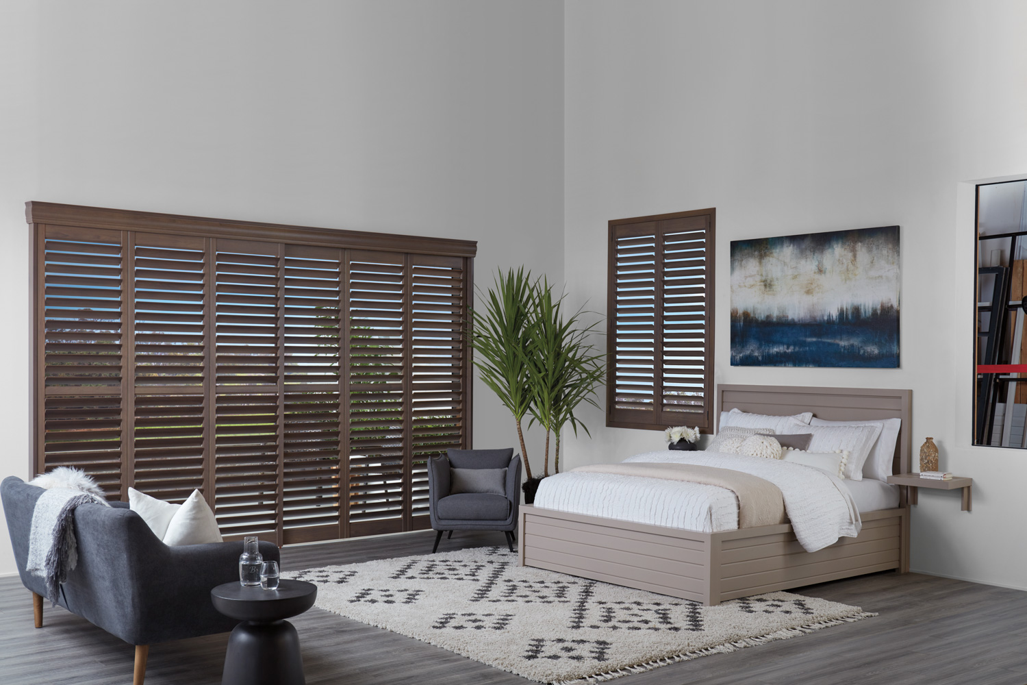 The bedroom is furnished with a bed, chair, and a painting, all of which showcase Composite Shutters.